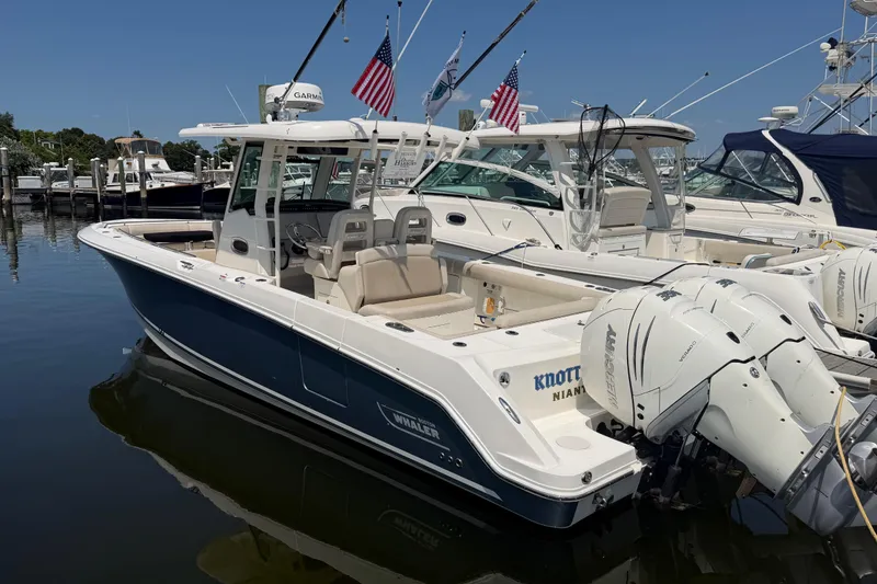Slide: The Image of 2017 Boston Whaler 330 Outrage boat docked, featuring triple Mercury engines and American flags. - 1