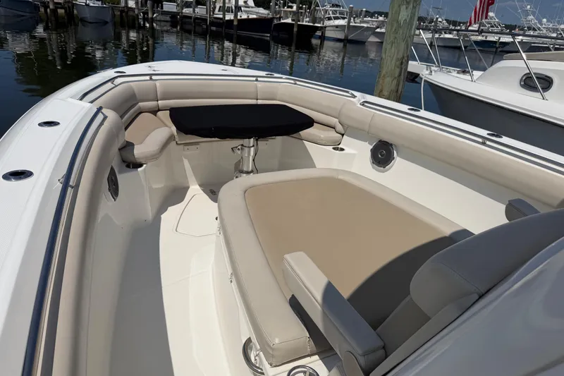 Slide: The Image of 2017 Boston Whaler 330 Outrage boat interior with cushioned seating and table, docked at marina. - 40