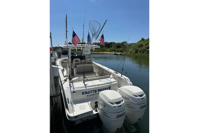 Slide: The Image of 2017 Boston Whaler 330 Outrage boat docked, featuring dual Mercury engines and fishing gear. - 6