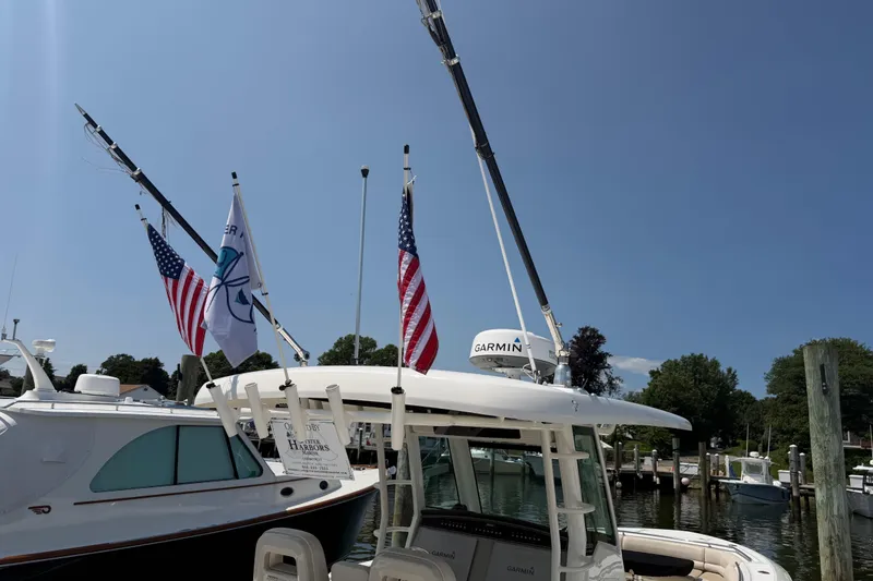 Slide: The Image of 2017 Boston Whaler 330 Outrage docked, featuring flags and Garmin equipment under a clear blue sky. - 51