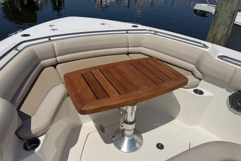 Slide: The Image of 2017 Boston Whaler 330 Outrage boat interior with cushioned seating and wooden table. - 44