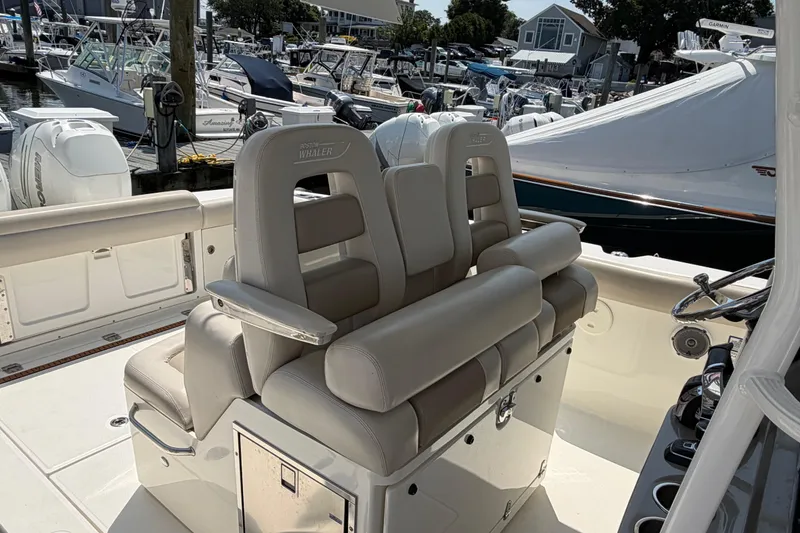 Slide: The Image of 2017 Boston Whaler 330 Outrage boat interior with luxurious seating at a marina. - 13