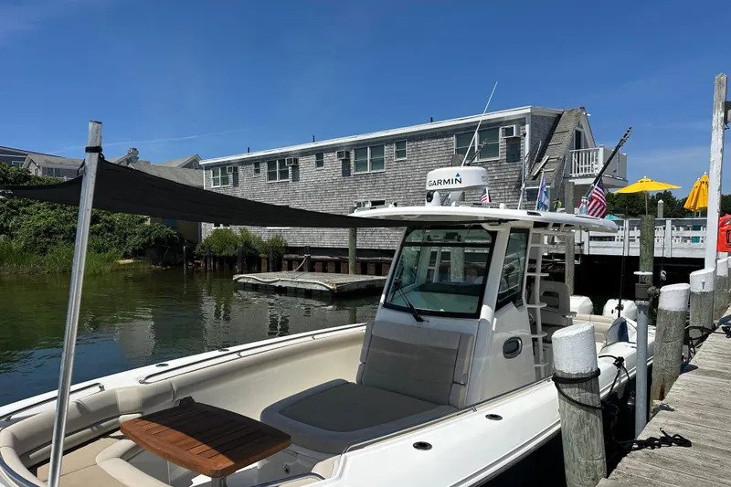 Slide: The Image of 2017 Boston Whaler 330 Outrage docked near waterfront buildings under clear blue sky. - 5