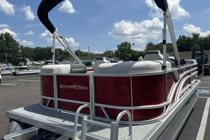 Slide: The Image of 2026 Bennington S Quad Bench 20 SSR pontoon boat with red exterior, parked outdoors. - 7