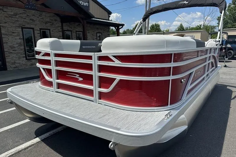 Slide: The Image of 2026 Bennington S Quad Bench 20 SSR pontoon boat with red and white design, parked outdoors. - 2