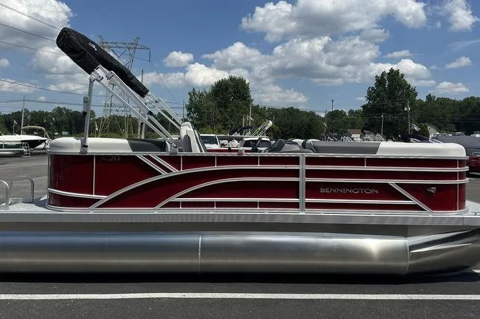 Slide: The Image of 2026 Bennington S Quad Bench 20 SSR pontoon boat, red and white, parked outdoors. - 9