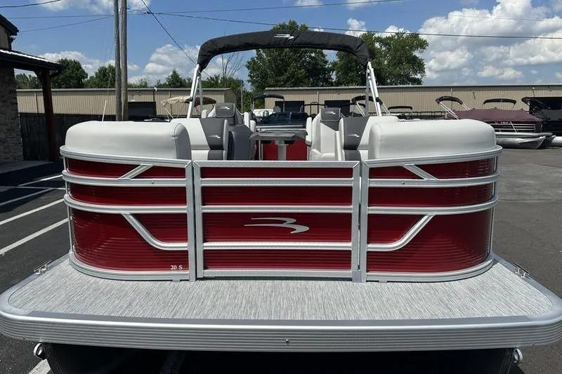 Slide: The Image of 2026 Bennington S Quad Bench 20 SSR pontoon boat, red and white design, parked outdoors. - 3