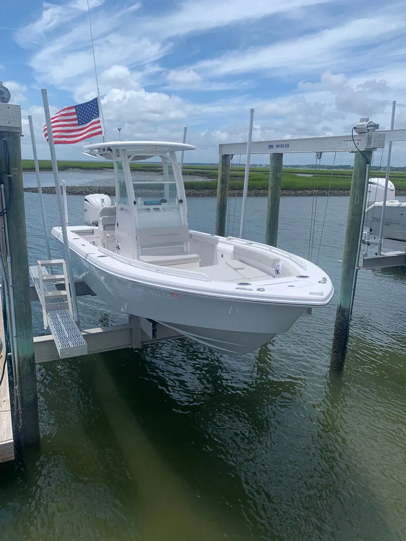 Slide: The Image of A 2023 Everglades 243 Center Console boat on a lift at the dock, with an American flag. - 4