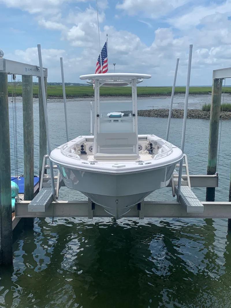 Slide: The Image of 2023 Everglades 243 Center Console on a boat lift, with American flag, in calm waters. - 7