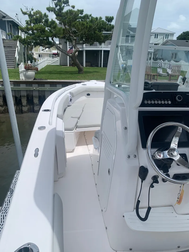 Slide: The Image of A modern boat with a helm, white seating, and sleek design, docked by a waterfront. - 41