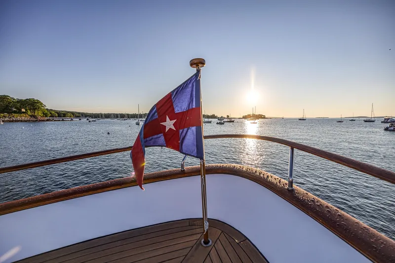 Slide: The Image of Deck view from 2004 Holland Jachtbouw Custom yacht at sunset, featuring a nautical flag. - 21