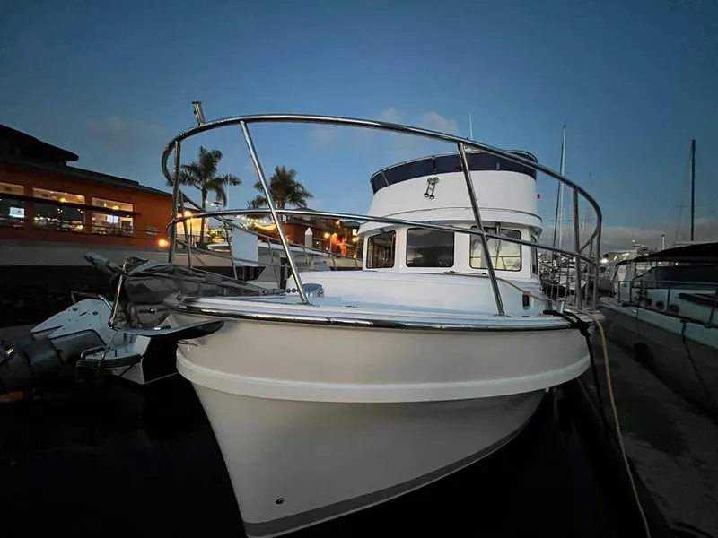 Slide: The Image of A modern boat with a white hull and blue cover docked in a lit marina. - 61