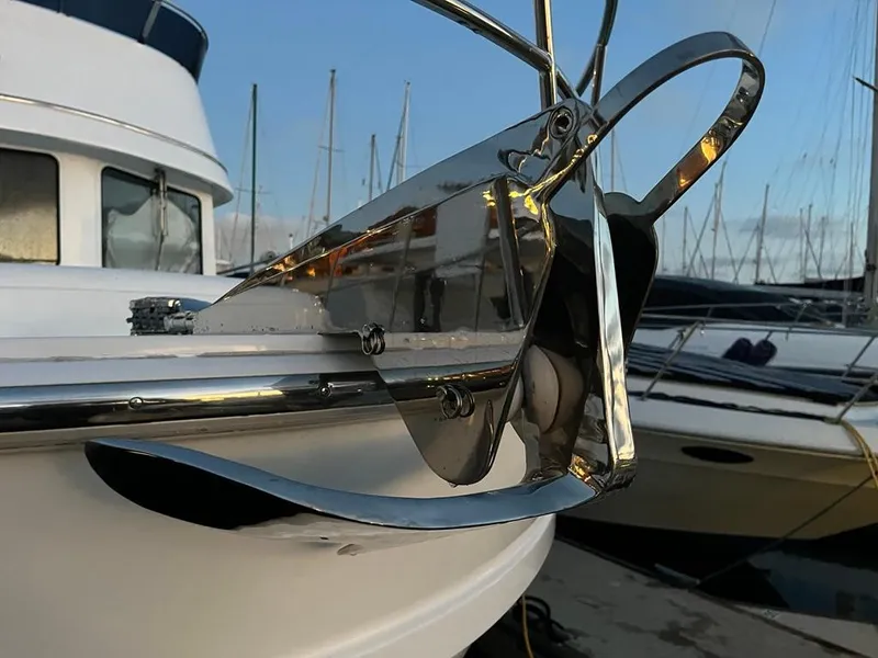 Slide: The Image of A shiny anchor is attached to the front of a boat, surrounded by other boats in the harbor. - 62