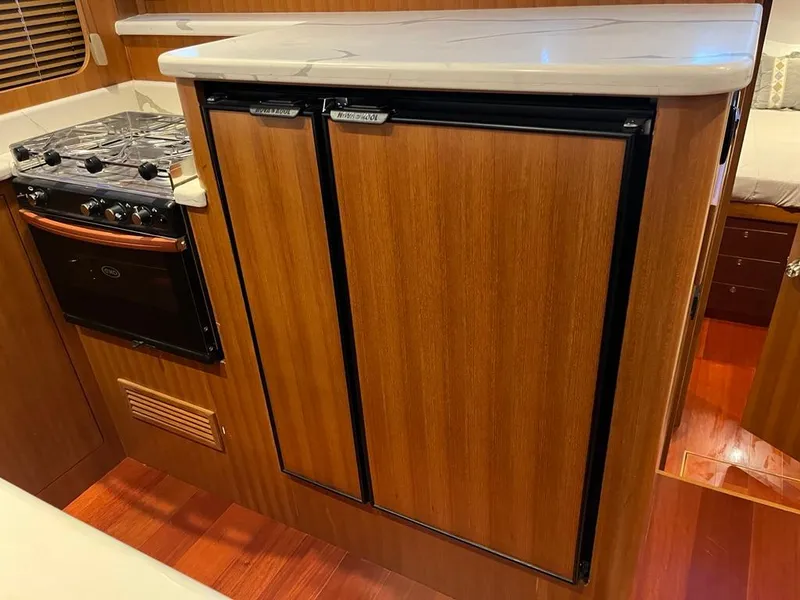 Slide: The Image of Compact kitchen area in 2025 Bracewell 41 boat with stove and wooden cabinetry. - 34