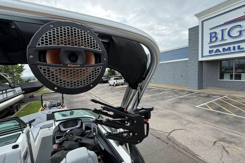 Slide: The Image of 2024 MasterCraft XT25 boat with Klipsch speaker, parked near a store. - 2
