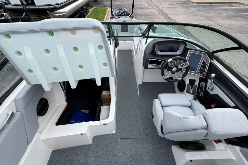 Slide: The Image of 2024 MasterCraft XT25 boat interior with helm, seating, and storage compartment. - 21