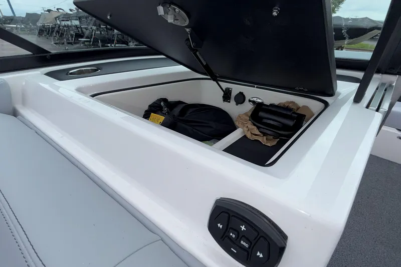 Slide: The Image of 2024 MasterCraft XT25 boat storage compartment with control panel and cup holder. - 12