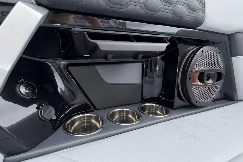 Slide: The Image of 2024 MasterCraft XT25 interior with speaker, cup holders, and sleek black paneling. - 20