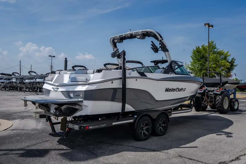 Slide: The Image of 2024 MasterCraft XT25 boat on trailer in parking lot, clear sky background. - 2
