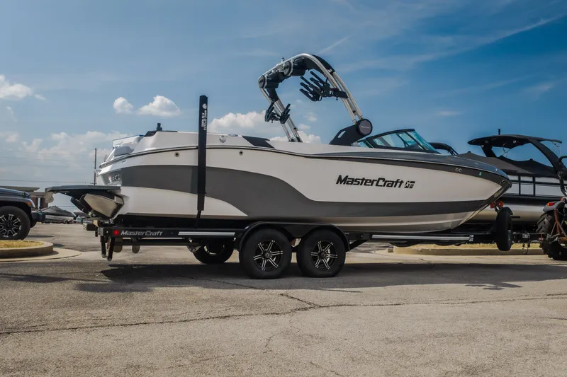 Slide: The Image of 2024 MasterCraft XT25 boat on trailer under clear blue sky. - 27