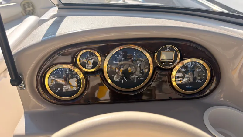 Slide: The Image of The dashboard of a 2002 Rinker 192 Captiva Bowrider with multiple gauges and a cup holder. - 21