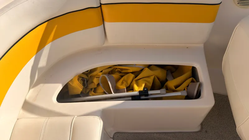 Slide: The Image of An open storage compartment in a boat with yellow upholstery, containing paddles and fabric. - 11