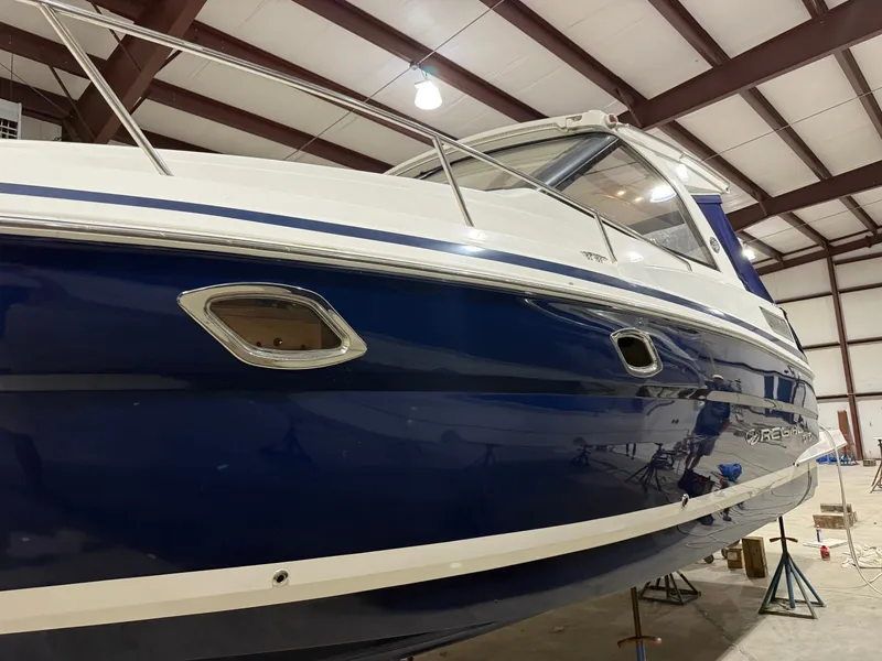 Slide: The Image of A 2018 Regal 35 Sport Coupe in a storage facility. The boat features a blue and white finish. - 12