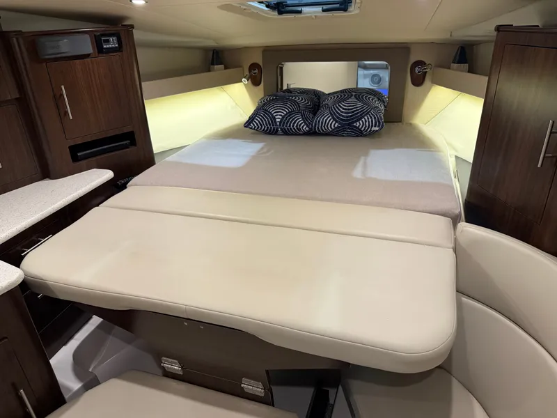 Slide: The Image of The cabin of the 2018 Regal 35 Sport Coupe features a cozy bed with pillows and wooden cabinetry. - 36
