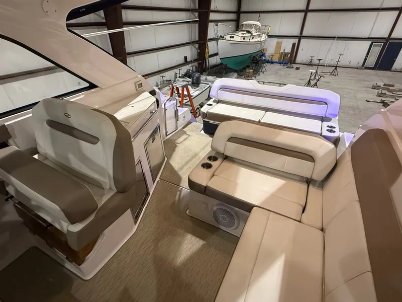 Slide: The Image of The image shows the cockpit of a 2018 Regal 35 Sport Coupe. It features beige upholstery and modern amenities. Another yacht is visible in the warehouse background. - 1