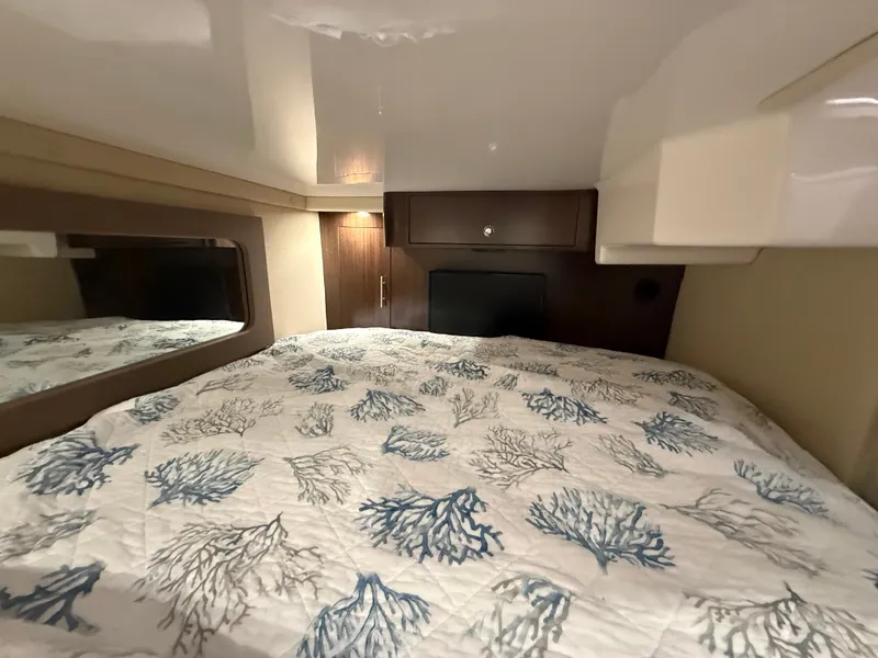 Slide: The Image of Interior of a 2018 Regal 35 Sport Coupe featuring a cozy bed with nautical-themed bedding. - 39