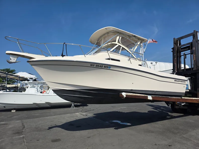 Slide: The Image of A 2022 Grady-White Gulfstream 232 boat is being moved by a forklift. It features a hardtop and cream-colored hull. - 2