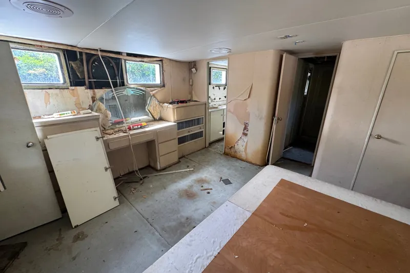 Slide: The Image of Interior of a 1981 Broward 72 Motor Yacht showing a worn and cluttered cabin space. - 34
