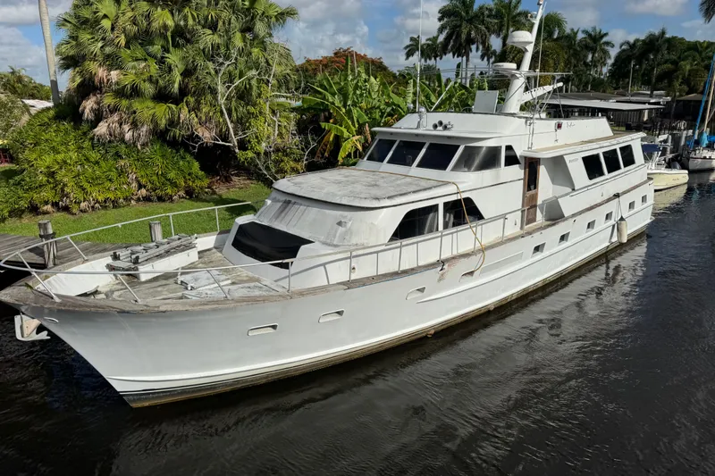 The Image of 1981 Broward 72 Motor Yacht docked near lush tropical foliage. - 0