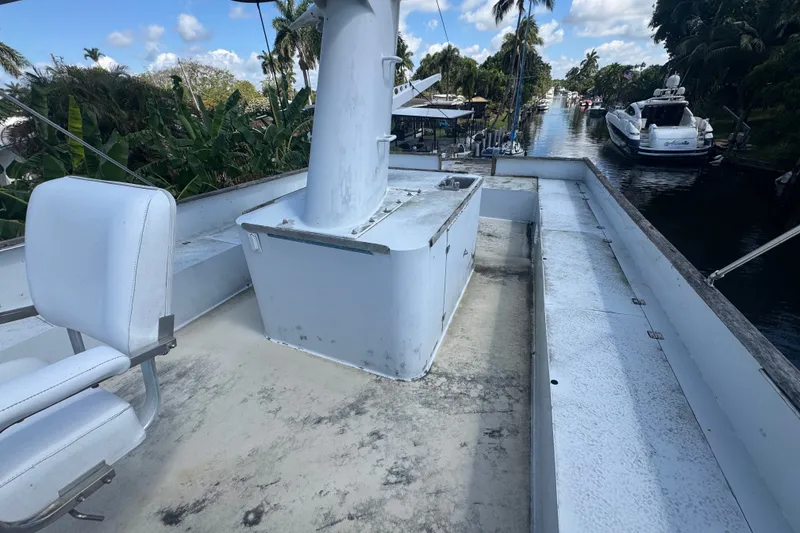 Slide: The Image of 1981 Broward 72 Motor Yacht deck view with seating, docked near lush greenery. - 15