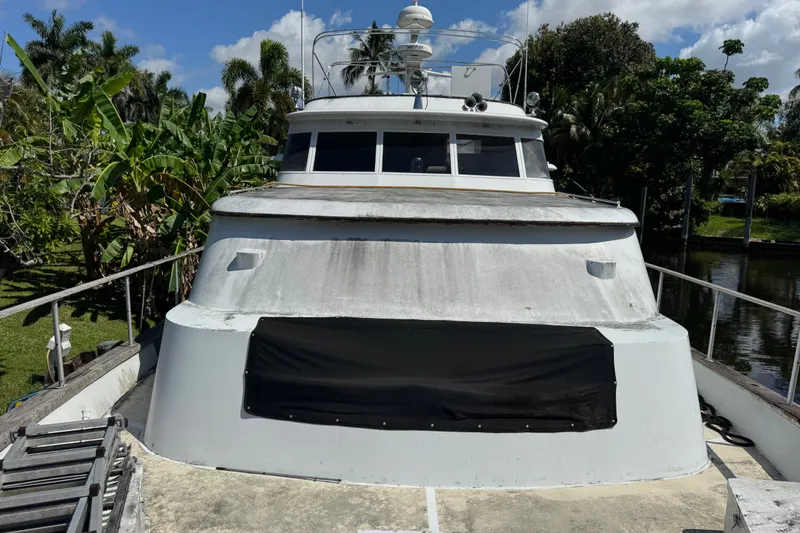 Slide: The Image of 1981 Broward 72 Motor Yacht docked, surrounded by lush tropical greenery under a clear blue sky. - 2