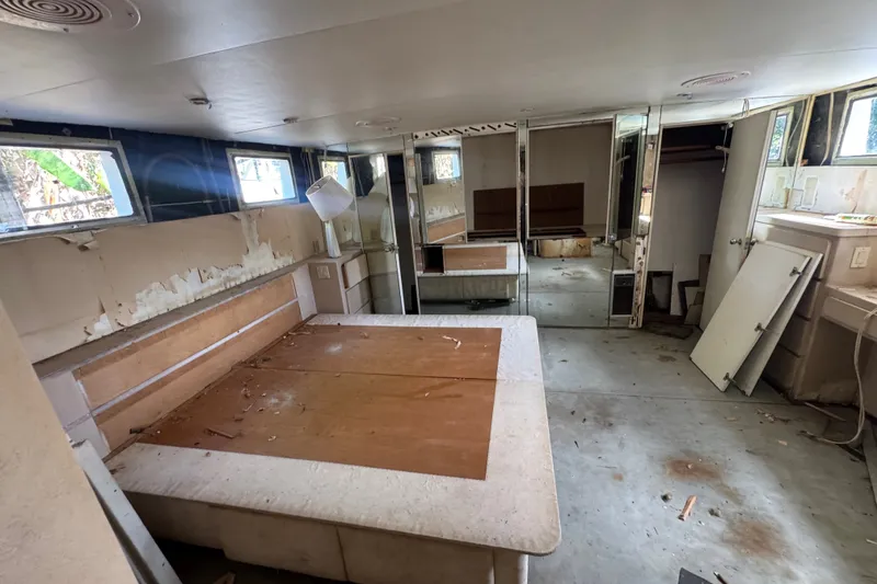 Slide: The Image of Interior of a 1981 Broward 72 Motor Yacht, showing a worn and unfinished cabin space. - 33