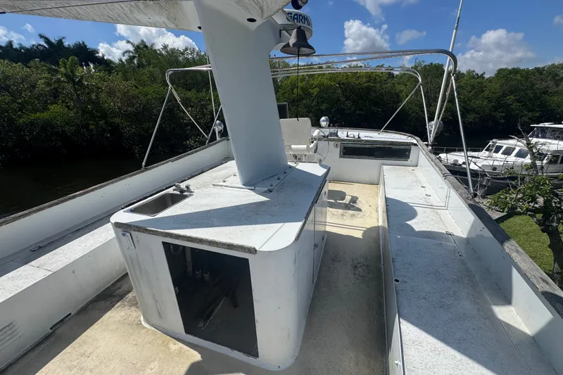Slide: The Image of 1981 Broward 72 Motor Yacht deck with sink, railing, and lush greenery background. - 14