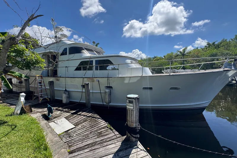 Slide: The Image of 1981 Broward 72 Motor Yacht docked by lush greenery under a bright blue sky. - 1