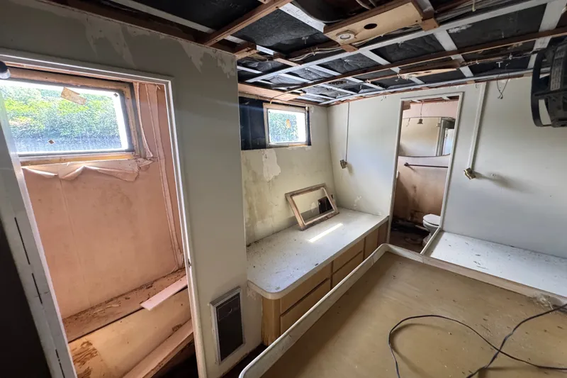 Slide: The Image of Interior of a 1981 Broward 72 Motor Yacht, showing a worn cabin with exposed ceiling. - 37