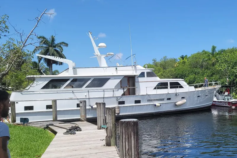 Slide: The Image of 1981 Broward 72 Motor Yacht docked by lush greenery and clear blue sky. - 0