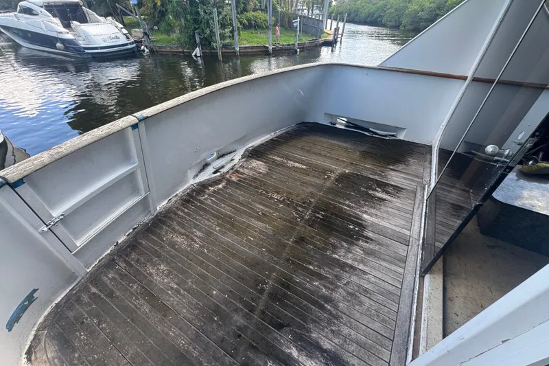 Slide: The Image of 1981 Broward 72 Motor Yacht deck with weathered wood and scenic waterway view. - 6