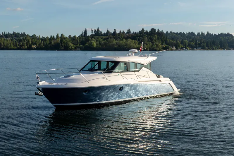 The Image of 2017 Tiara Yachts C39 Coupe cruising on a serene lake with forested shoreline. - 0