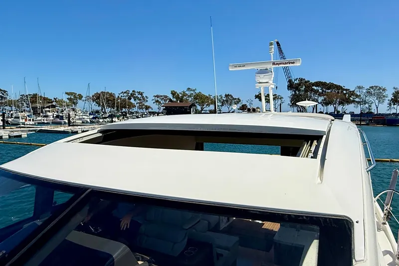 Slide: The Image of 2016 Sea Ray Sundancer 400 yacht with open sunroof, docked at marina under clear blue sky. - 62