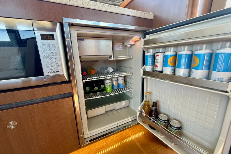 Slide: The Image of Open fridge in 2016 Sea Ray Sundancer 400 yacht kitchen, stocked with beverages and a microwave. - 23