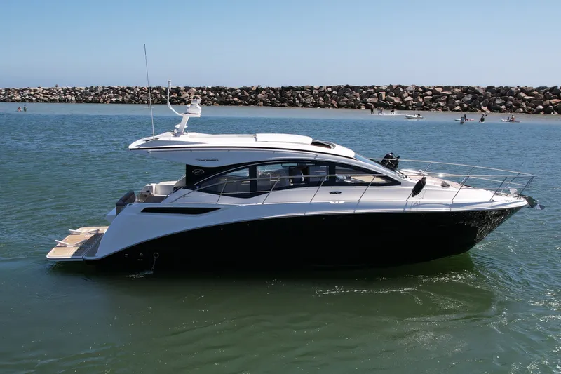 Slide: The Image of 2016 Sea Ray Sundancer 400 yacht cruising in calm waters near a rocky shoreline. - 5