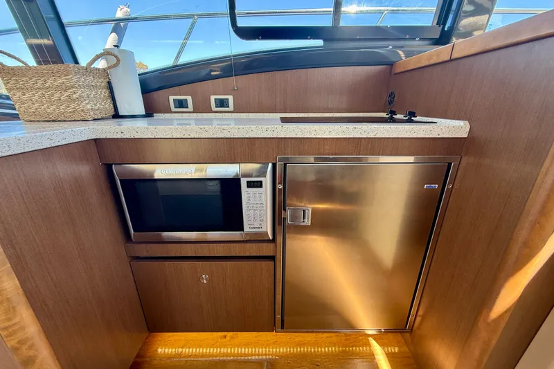 Slide: The Image of 2016 Sea Ray Sundancer 400 yacht kitchen with microwave, fridge, and countertop. - 24