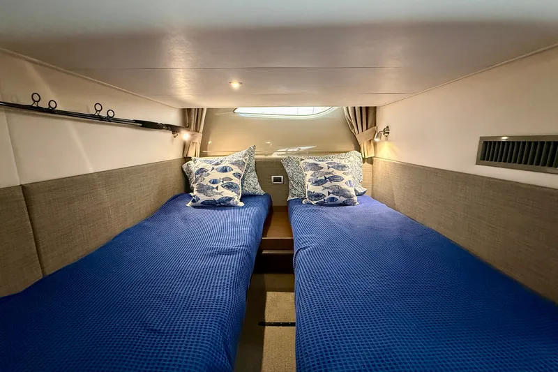 Slide: The Image of Cabin interior of 2016 Sea Ray Sundancer 400 with twin beds and nautical-themed pillows. - 45