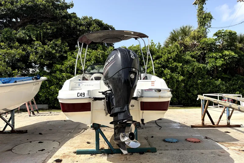 Slide: The Image of 2019 Tahoe 550 TS boat with Mercury engine on a stand, surrounded by greenery. - 6