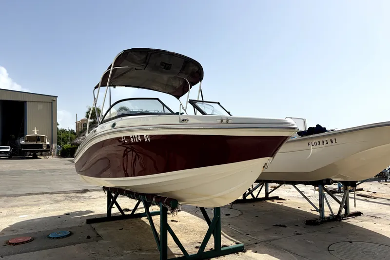 The Image of 2019 Tahoe 550 TS boat on dry dock, with canopy, in a marina setting. - 0