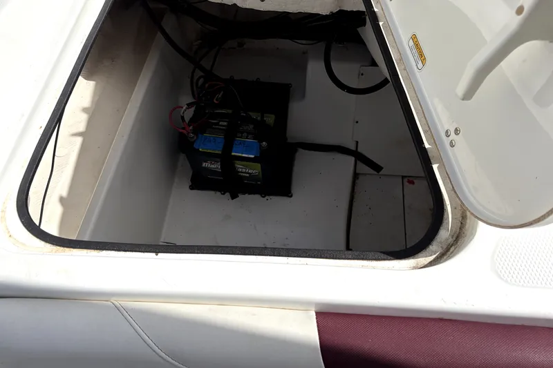 Slide: The Image of Open storage compartment in a 2019 Tahoe 550 TS boat, revealing a secured battery. - 13